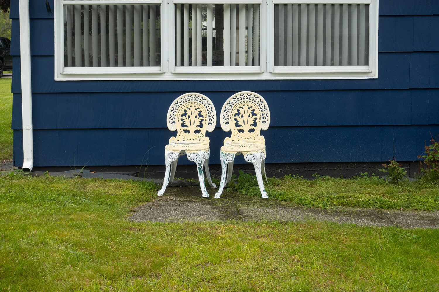 Wrought-iron chairs in front of blue house